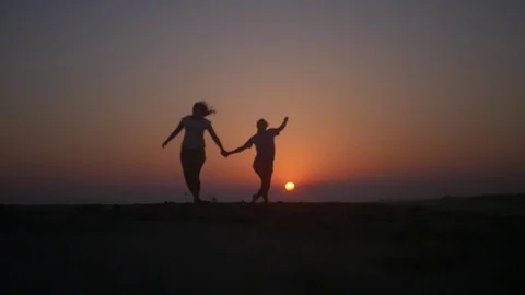 two best friends holding hands in the sunset