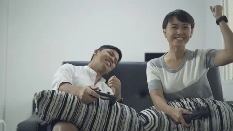 Two friends with joysticks playing video game on couch at home. Stock Footage 233302389
