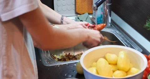 Two friends in the kitchen are peeling vegetables with knives Stock Footage 169991295