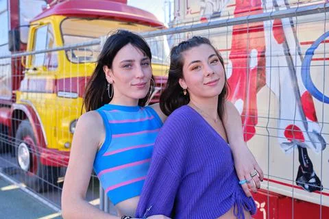 Two friends looking to the camera standing in the street next to a circus parade Stock Photos