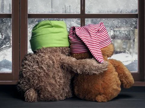 Two friends looking out the window at the falling snow and the city. Toys col Stock Photos
