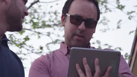 Two friends looking at a tablet computer together - Online Media Stock Footage 49871960
