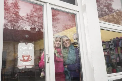 Two friends looking through window and drinking coffee in coffee shop, Bavaria, Stock Photos