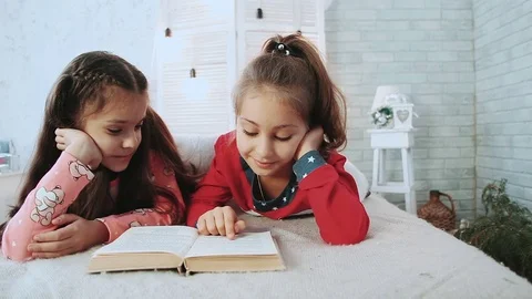 Two friends lying and reading a book Stock Footage 71090253