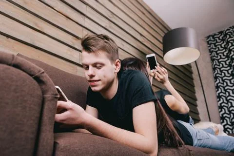 Two friends lying in bed and using smartphone Stock Photos