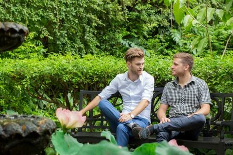 Two friends men talking sitting in a garden. Stock Photos