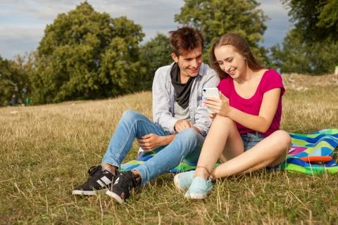 Two friends in a park with mobile phone. Summer time. Stock Photos