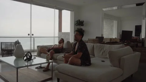 Two friends playing video games in the living room of a beach house with Stock Footage 186200085