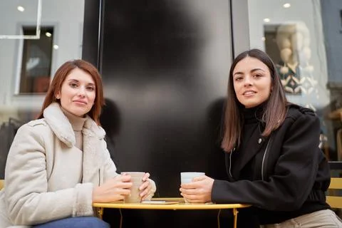 Two friends posing for the camera while having a coffee in a city coffee shop Foto stock