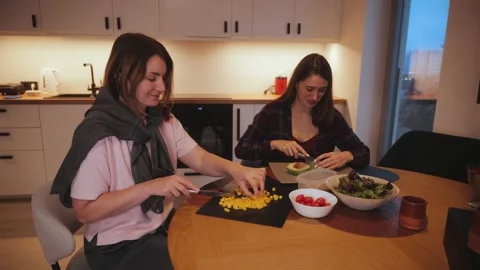 Two friends prepare a meal together in a kitchen at night Stock Footage 341508045