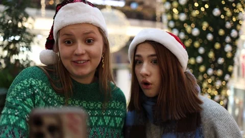 Two friends in santa hats react to surprising holiday news while standing  Stock Footage 325212378
