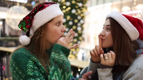 Two friends in santa hats sharing secrets and gossiping together Video stock 325212438