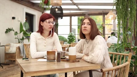 Two friends sit in a cozy cafe both looking away  Stock Footage 320827262