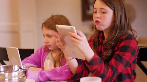 Two friends sitting at a kitchen island using their tablets Stock Footage 63207984