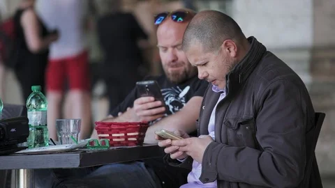 Two friends sitting at the restaurant using smartphones Stock Footage 84035523