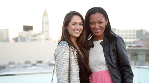 Two friends standing on a rooftop smile into the camera Vídeos de archivo 44168535