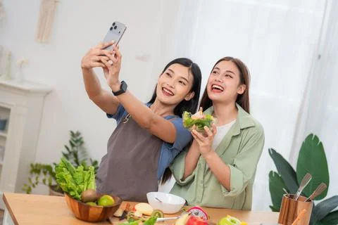 Two friends take a selfie while preparing a healthy meal in a kitchen durin.. Stock Photos