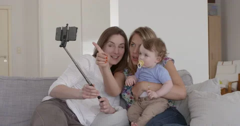 Two friends taking a selfie with 1 year old baby Video stock 48627589