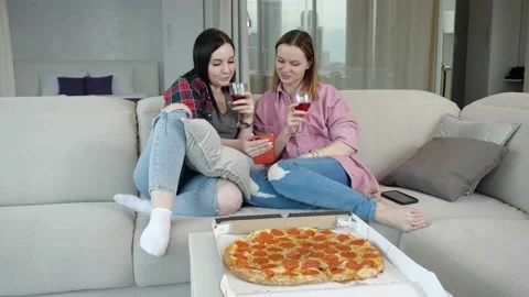 Two friends talk cheerfully, drink red wine, eat pizza and relax Stock Footage 153419674
