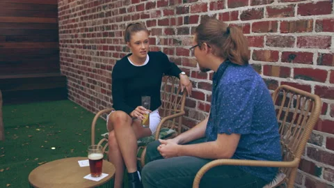 Two friends talk seriously about life issues on patio outside a pub over beers. Stock Footage 199457013