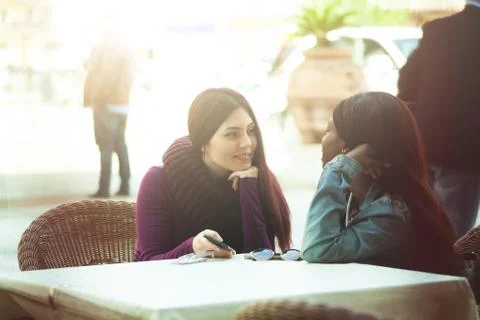 Two friends talking and using the mobile phone. Stock Photos