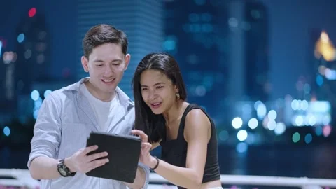 Two friends using digital tablet tapping touch screen, city night lights Stock Footage 276798847