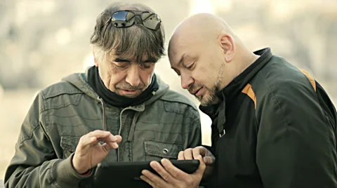 Two friends using smartphone with tablet computer. Technology Stock Footage 34278235