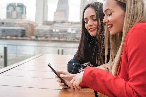 Two friends using their mobile phone while sitting at coffee shop. Foto stock