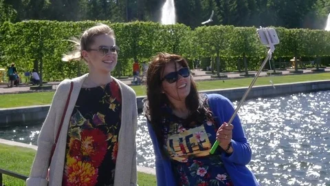 Two friends walking in the park and taking a photo on the phone by a beautiful Stock Footage 78537347