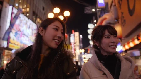 Two friends walking through bright Japanese streets dotombori  Vídeo Stock 84875068