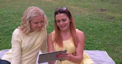 Two friends watching a tablet in the park Stock Footage 68306778