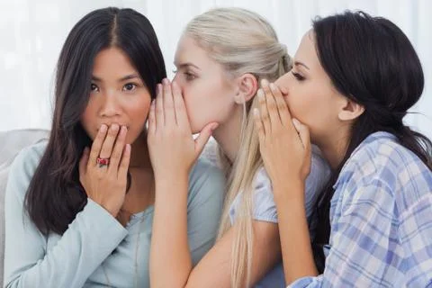 Two friends whispering secrets to surprised brunette Stock Photos