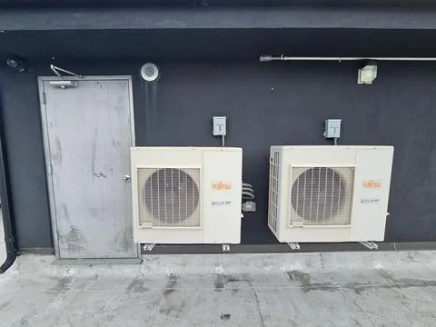 Two Fujitsu Mini Split Condensers on a Black Building Wall in Brooklyn Stock Photos