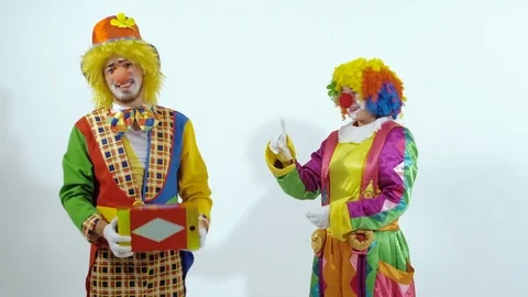Two funny circus clowns playing with a red glossy box, throwing it to the air Stock-Footage 70284236