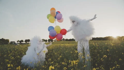 Two funny clowns mime in white air suits on stilts and with colored balloons wal Stock Footage 92194352