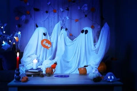 Two funny ghosts in white sheets holding Boo sign at Halloween party at hom.. 写真素材