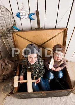 Two funny little girls inside big wooden chest Stock Photos