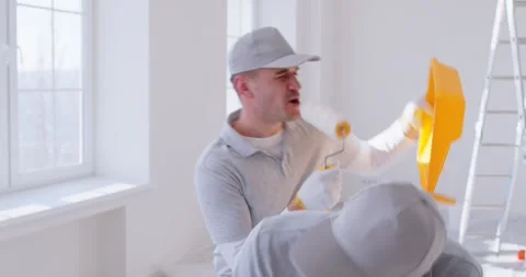 Two funny painters are having fun, singing and dancing in room undergoing Stock Footage 332824245