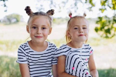 Two funny sisters look at the camera in a summer park outdoors Stock Photos