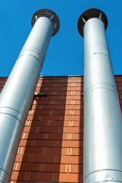 Two galvanized chimneys on the facade of a red brick building, vertical photo Stock Photos
