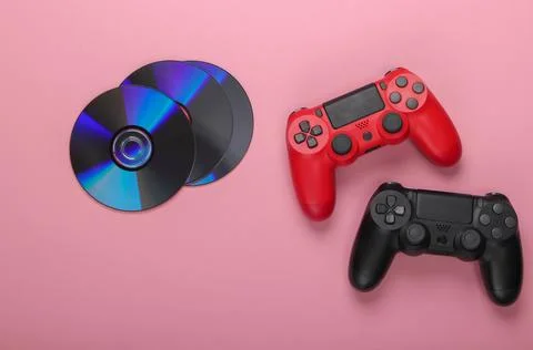 Two gamepads and cd compact discs on a pink pastel background. Gaming, entert 写真素材