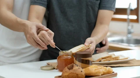 Two gay help to smear jam on to sliced bread in the kitchen Stock-Footage 125815528