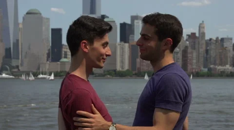 Two gay men, close-up, embrace in front of a Manhattan cityscape. Stock Footage