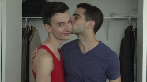 Two gay men come out of a closet, embrace and kiss. Stock Footage