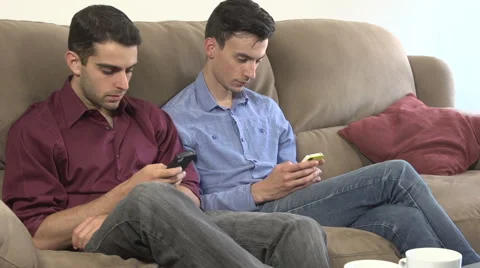 Two gay men, in two-shot, look at phones in silence Stock Footage 44111030
