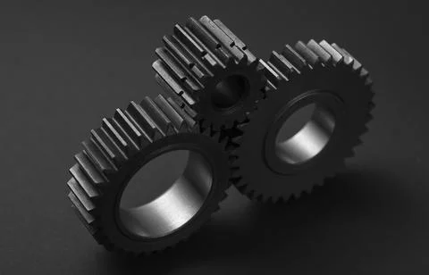 Two gears rest on a dark gray surface Stock Photos