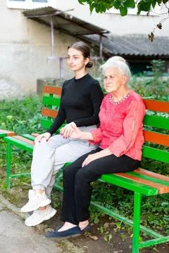 Two generations connect on a bench in the park as the warm afternoon sun ca.. Foto stock