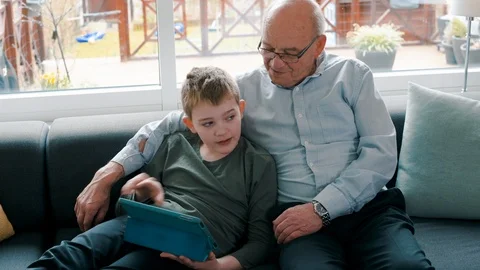 Two generations enjoys spending time together watching content on tablet at home Stock Footage 105130408