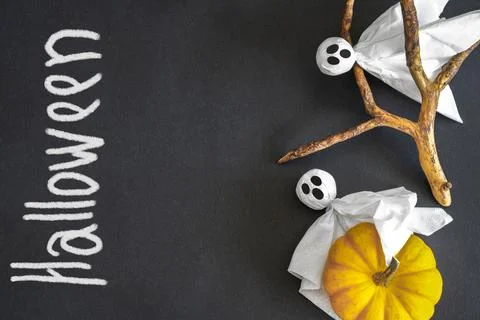 Two ghosts, pumpkin, black background with inscription Halloween. Copy space. Stock Photos