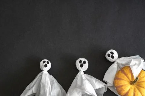 Two ghosts, pumpkin on black background. Top view. Copy space. Stock Photos